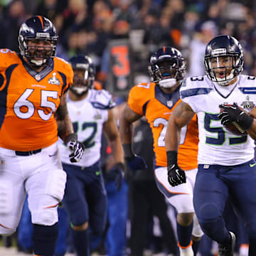 Feb 2, 2014; East Rutherford, NJ, USA; Seattle Seahawks outside linebacker Malcolm Smith (53) runs for a touchdown after an interception against Denver Broncos guard Louis Vasquez (65) during the first half in Super Bowl XLVIII at MetLife Stadium.  Mandatory Credit: Brad Penner-Imagn Images