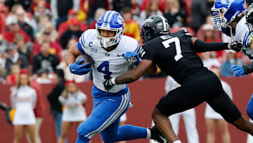 BYU's LJ Martin (4-white) runs the ball past Iowa State's Tre Bell (7-black) in a game at Jack Trice Stadium