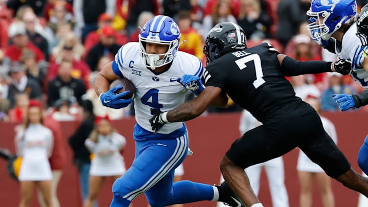 BYU's LJ Martin (4-white) runs the ball past Iowa State's Tre Bell (7-black) in a game at Jack Trice Stadium