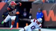 Nov 23, 2025; Cincinnati, Ohio, USA; Cincinnati Bengals running back Chase Brown (30) leaps over New England Patriots cornerback Christian Gonzalez (0) on a carry in the second quarter at Paycor Stadium. Mandatory Credit: Sam Greene-USA TODAY Network via Imagn Images