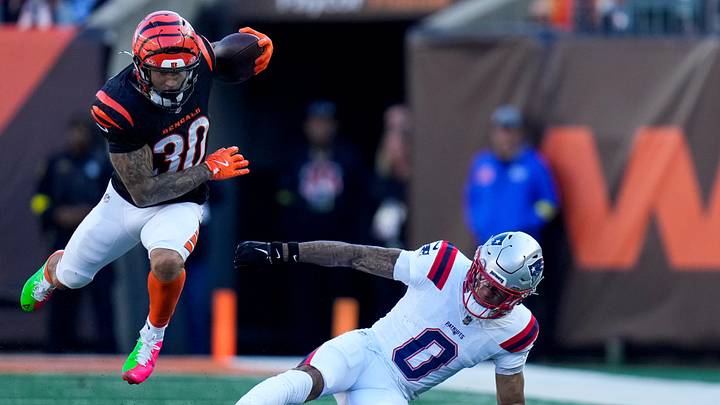 Cincinnati Bengals running back Chase Brown (30) leaps over New England Patriots cornerback Christian Gonzalez (0) on a carry in the second quarter of the NFL Week 12 game between the Cincinnati Bengals and the New England Patriots at Paycor Stadium in downtown Cincinnati on Sunday, Nov. 23, 2025.