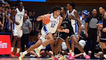 Nov 21, 2025; Durham, North Carolina, USA; Duke Blue Devils forward Cameron Boozer (12) drives to the basket as Niagara Purple Eagles forward Justin Hawkins (0) defends during the first half at Cameron Indoor Stadium. Mandatory Credit: Rob Kinnan-Imagn Images
