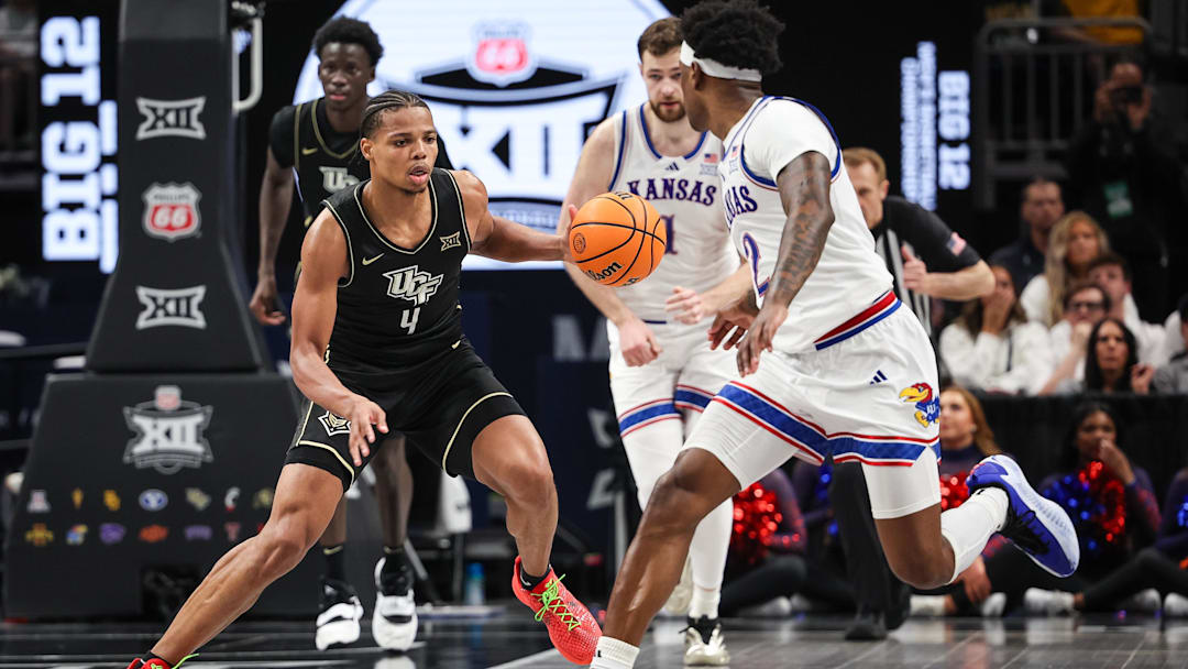 Mar 12, 2025; Kansas City, MO, USA; UCF Knights guard Keyshawn Hall (4) brings the ball up court around Kansas Jayhawks guard AJ Storr (2) during overtime at T-Mobile Center. Mandatory Credit: William Purnell-Imagn Images
