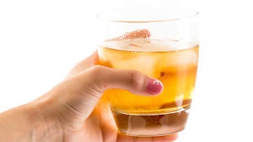 Hand holding an old fashioned glass with whisky on the rocks...