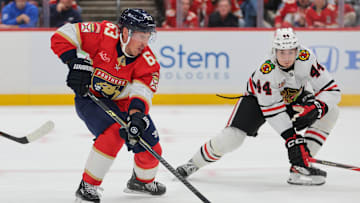 Oct 7, 2025; Sunrise, Florida, USA; Florida Panthers left wing Brad Marchand (63) moves the puck against Chicago Blackhawks defenseman Wyatt Kaiser (44) during the first period at Amerant Bank Arena. Mandatory Credit: Sam Navarro-Imagn Images