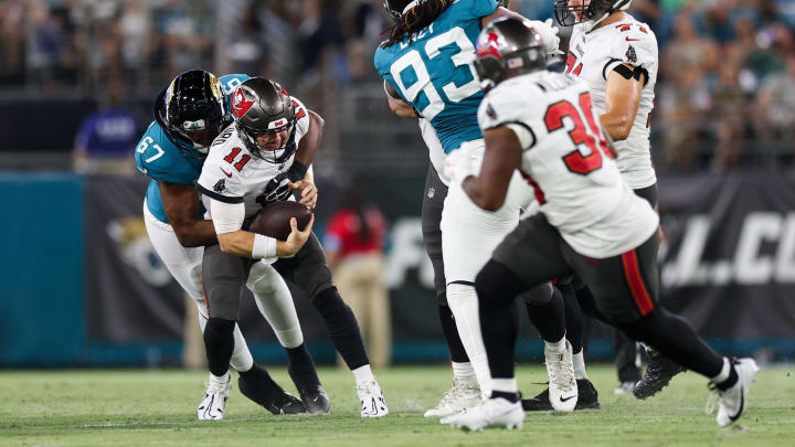 Aug 17, 2024; Jacksonville, Florida, USA; Tampa Bay Buccaneers quarterback John Wolford (11) is sacked by Jacksonville Jaguars defensive end Breeland Speaks (67) in the fourth quarter during a preseason game at EverBank Stadium. Mandatory Credit: Nathan Ray Seebeck-USA TODAY Sports