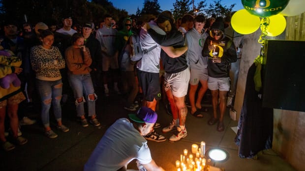 People leave candles at the entrance to Autzen Stadium during a candlelight vigil in remembrance of Oregon's Spencer Webb.
