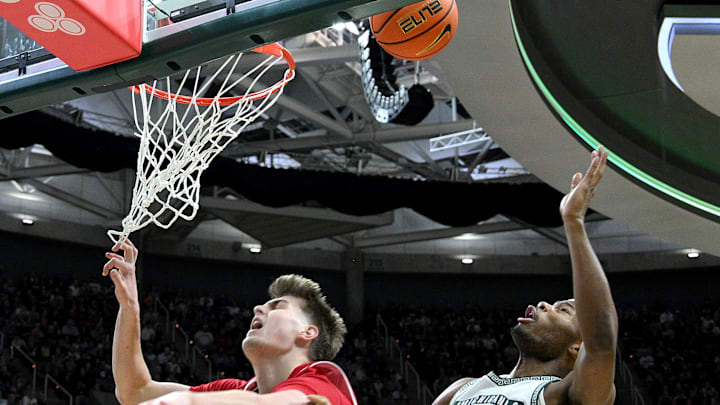 Mar 2, 2025; East Lansing, Michigan, USA;  Wisconsin Badgers forward Nolan Winter (31) can’t get this shot to go while defended by Michigan State Spartans guard Tre Holloman (5) during the first half at Jack Breslin Student Events Center. Mandatory Credit: Dale Young-Imagn Images