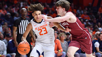 Nov 14, 2025; Champaign, Illinois, USA;  Illinois Fighting Illini guard Keaton Wagler (23) drives the ball against Colgate Raiders guard Ben Tweedy (6) during the first half at State Farm Center. Mandatory Credit: Ron Johnson-Imagn Images
