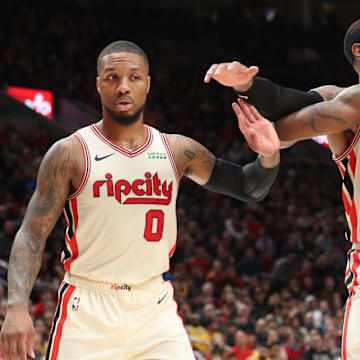 Dec 28, 2019; Portland, Oregon, USA; Portland Trail Blazers guard Damian Lillard (0) raises his hand as teammate Trail Blazers' forward Carmelo Anthony (00) holds Los Angeles Lakers forward LeBron James (23) in the second half at Moda Center. Mandatory Credit: Jaime Valdez-Imagn Images