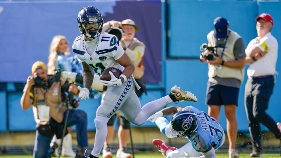 Jaxon Smith-Njigba runs with a Titans defender on the ground.