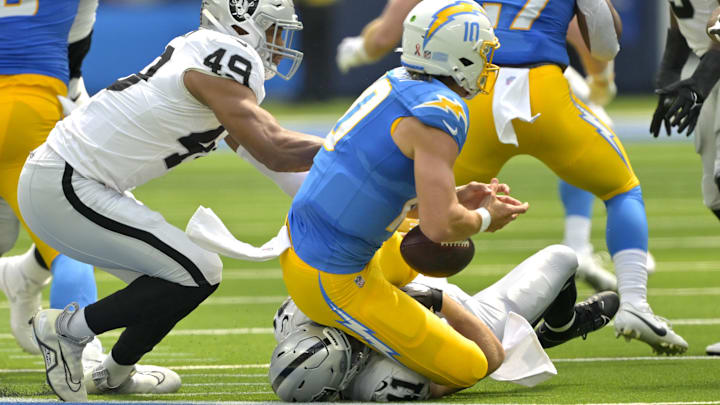 Sep 8, 2024; Inglewood, California, USA; Los Angeles Chargers quarterback Justin Herbert (10) is sacked by Las Vegas Raiders defensive end Charles Snowden (49) and linebacker Robert Spillane (41) in the first half at SoFi Stadium. Mandatory Credit: Jayne Kamin-Oncea-Imagn Images