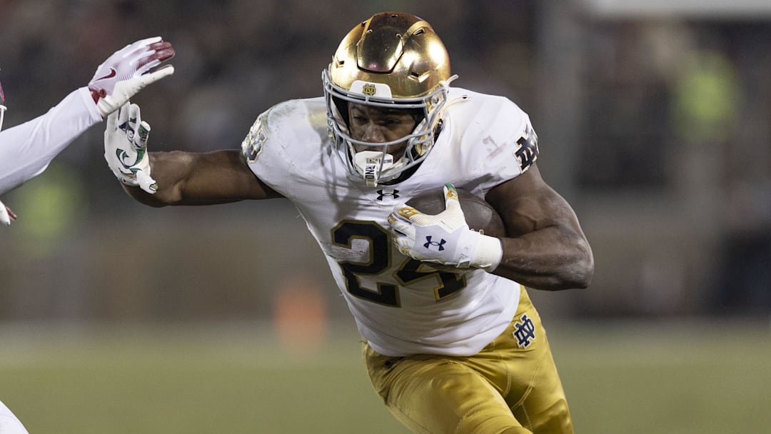 Nov 29, 2025; Stanford, California, USA; Notre Dame Fighting Irish running back Jadarian Price (24) runs with the football against Stanford Cardinal safety Darrius Davis (29) during the first quarter at Stanford Stadium. Nov 29, 2025; Stanford, California, USA; Notre Dame Fighting Irish running back Jadarian Price (24) runs with the football against Stanford Cardinal safety Darrius Davis (29) during the first quarter at Stanford Stadium.