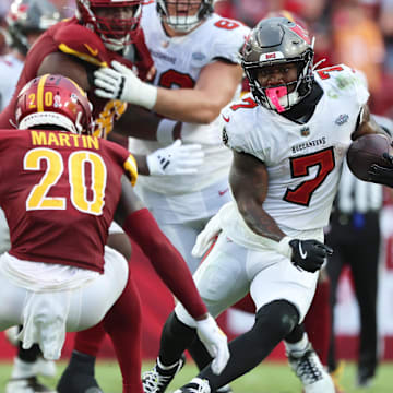 Sep 8, 2024; Tampa, Florida, USA;  Tampa Bay Buccaneers running back Bucky Irving (7) runs with the ball as Washington Commanders safety Quan Martin (20) defends during the second half at Raymond James Stadium. Mandatory Credit: Kim Klement Neitzel-Imagn Images