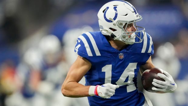 Colts wide receiver Alec Pierce (blue uniform with white helmet/numbers) runs with the brown football after catching a pass. 