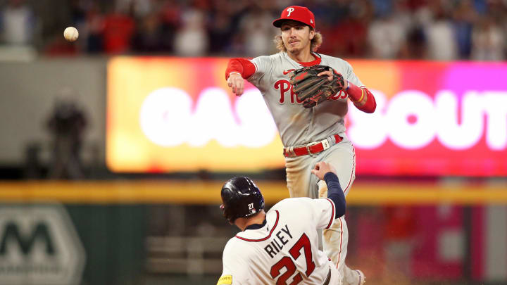 Oct 7, 2023; Cumberland, Georgia, USA; Philadelphia Phillies second baseman Bryson Stott (5) turns a double play over Atlanta Braves third baseman Austin Riley (27) during the eighth inning during game one of the NLDS for the 2023 MLB playoffs at Truist Park