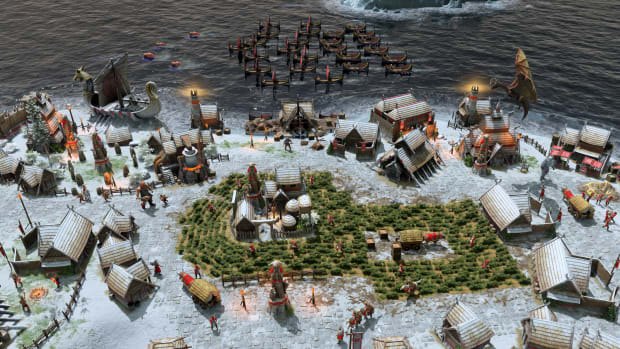 Age of Mythology: Retold screenshot of a snowy village with a fleet of ships anchoring off the shore.