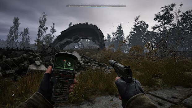 Stalker 2 screenshot of holding a scanner in one hand and a pistol in the other looking at the ruin of a building.