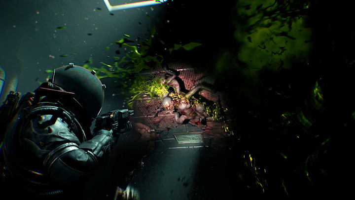 The protagonist of Cronos firing his weapon at a writing mass of human body parts, green blood spurting out of it. 