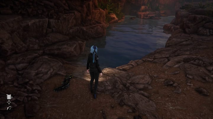Eve standing in front of a lake among some rocks.