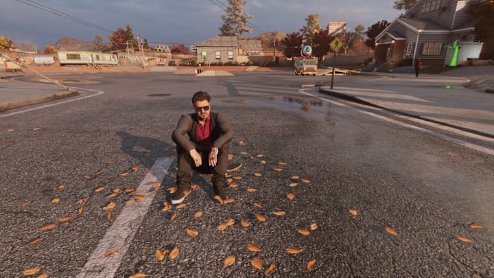 Bam Margera sits on his skateboard in an empty street in THPS 3+4