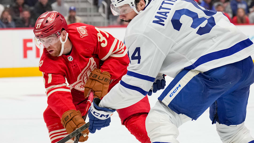 Detroit Red Wing forwards Andrew Copp (18) and J.T. Compher (37) battle Toronto Maple Leafs forward Auston Matthews (34) for the puck. Detroit Red Wing forwards Andrew Copp (18) and J.T. Compher (37) battle Toronto Maple Leafs forward Auston Matthews (34) for the puck.