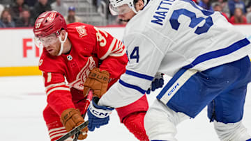 Detroit Red Wing forwards Andrew Copp (18) and J.T. Compher (37) battle Toronto Maple Leafs forward Auston Matthews (34) for the puck.