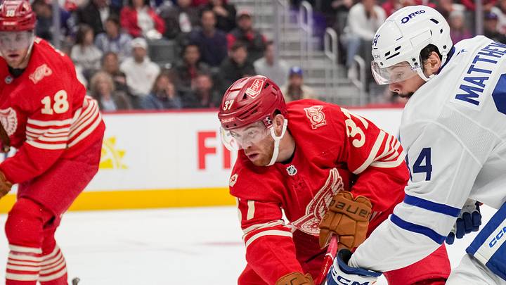 Detroit Red Wing forwards Andrew Copp (18) and J.T. Compher (37) battle Toronto Maple Leafs forward Auston Matthews (34) for the puck.