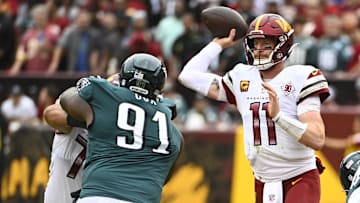 Sep 25, 2022; Landover, Maryland, USA; Washington Commanders quarterback Carson Wentz (11) passes as Philadelphia Eagles defensive tackle Fletcher Cox (91) defends during the second half at FedExField. Mandatory Credit: Brad Mills-Imagn Images