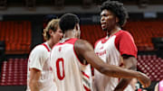 Indiana basketball forward Sam Alexis (right) chest bumps guard Jasai Miles (middle) while forward Reed Bailey (left) smiles.