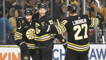 May 12, 2024; Boston, Massachusetts, USA; Boston Bruins center Pavel Zacha (18) and defenseman Hampus Lindholm (27) react with defenseman Brandon Carlo (25) after Carlos goal during the first period in game four of the second round of the 2024 Stanley Cup Playoffs against the Florida Panthers at TD Garden. Mandatory Credit: Bob DeChiara-USA TODAY Sports