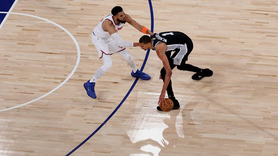 San Antonio Spurs forward Victor Wembanyama dribbles the ball against New York Knicks center Karl-Anthony Towns.