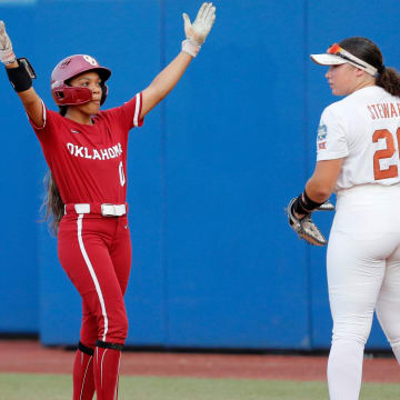 Oklahoma outfielder Rylie Boone (0) celebrates a single next to Texas' Katie Stewart (20) in the fourth inning of Game 2 of the NCAA softball Women's College World Series Championship Series game between the Oklahoma Sooners (OU) and Texas Longhorns at Devon Park in Oklahoma City, Thursday, June, 6, 2024.