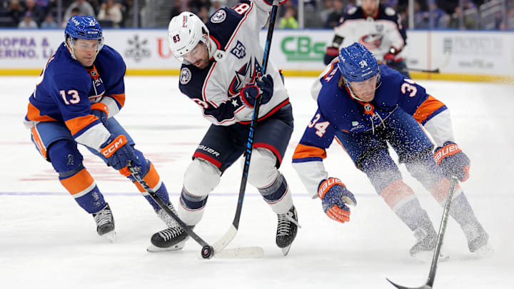 Mar 22, 2026; Elmont, New York, USA; Columbus Blue Jackets right wing Conor Garland (83) skates with the puck between New York Islanders center Mathew Barzal (13) and defenseman Adam Boqvist (34) during the third period at UBS Arena. Mandatory Credit: Brad Penner-Imagn Images