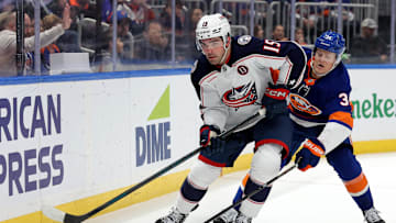 Mar 24, 2025; Elmont, New York, USA; Columbus Blue Jackets defenseman Dante Fabbro (15) skates with the puck against New York Islanders defenseman Adam Boqvist (34) during the second period at UBS Arena. Mandatory Credit: Brad Penner-Imagn Images