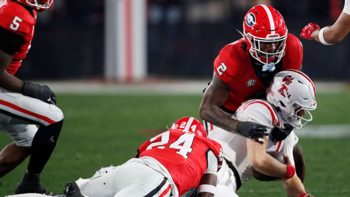 Georgia defensive back Malaki Starks (24) and Georgia linebacker Smael Mondon Jr. (2) take down Ole Miss quarterback Jaxson Dart (2) during the first half of a NCAA college football game against Ole Miss in Athens, Ga., on Saturday, Nov. 11, 2023.