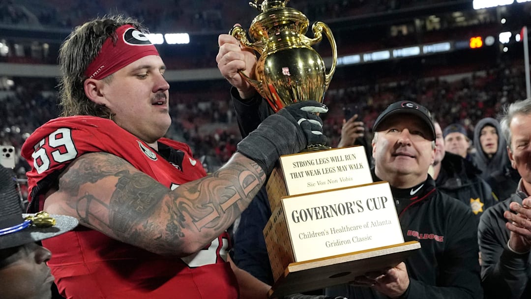 Georgia coach Kirby Smart hands the governor cup to Georgia offensive lineman Tate Ratledge (69) after Georgia won a NCAA college football game against Georgia Tech in overtime in Athens, Ga., on Friday, Nov. 29, 2024. Georgia won 44-42.
