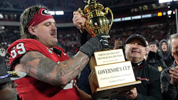 Georgia coach Kirby Smart hands the governor cup to Georgia offensive lineman Tate Ratledge (69) after Georgia won a NCAA college football game against Georgia Tech in overtime in Athens, Ga., on Friday, Nov. 29, 2024. Georgia won 44-42.