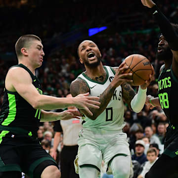 Dec 6, 2024; Boston, Massachusetts, USA;  Milwaukee Bucks guard Damian Lillard (0) drives to the basket between Boston Celtics guard Payton Pritchard (11) and center Neemias Queta (88) during the first half at TD Garden. Mandatory Credit: Bob DeChiara-Imagn Images