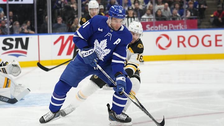 Jan 4, 2025; Toronto, Ontario, CAN; Toronto Maple Leafs forward John Tavares (91) battles with Boston Bruins forward Pavel Zacha (18) to get control of the puck during the first period at Scotiabank Arena. Mandatory Credit: John E. Sokolowski-Imagn Images