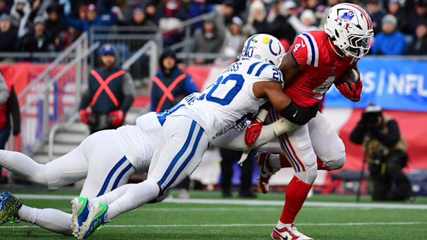 Colts safety Nick Cross (white uniform with blue trim) makes a tackle on a Patriots ball-carrier.