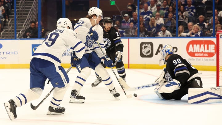 Apr 17, 2024; Tampa, Florida, USA; Toronto Maple Leafs right wing Pontus Holmberg (29) passes the puck as Tampa Bay Lightning goaltender Matt Tomkins (90) defends and Toronto Maple Leafs left wing Matthew Knies (23) and Tampa Bay Lightning defenseman Matt Dumba (24) look on during the second period at Amalie Arena. Mandatory Credit: Kim Klement Neitzel-USA TODAY Sports