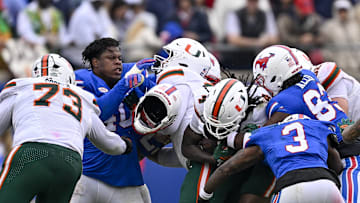 Nov 1, 2025; Dallas, Texas, USA;  SMU Mustangs defensive lineman Keveion'Ta Spears (40) loses his helmet as the defense tackles Miami Hurricanes running back Mark Fletcher Jr. (4) during the second quarter at Gerald J. Ford Stadium. Mandatory Credit: Jerome Miron-Imagn Images