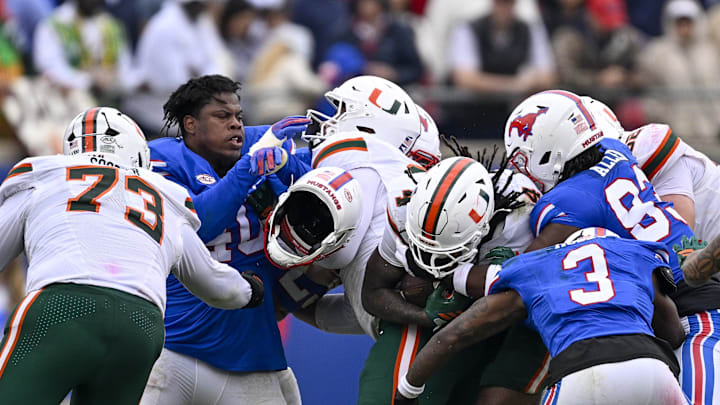 Nov 1, 2025; Dallas, Texas, USA;  SMU Mustangs defensive lineman Keveion'Ta Spears (40) loses his helmet as the defense tackles Miami Hurricanes running back Mark Fletcher Jr. (4) during the second quarter at Gerald J. Ford Stadium. Mandatory Credit: Jerome Miron-Imagn Images