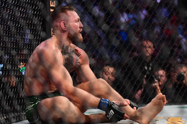 Conor McGregor holds his leg after suffering an injury against Dustin Poirier during UFC 264 at T-Mobile Arena. 