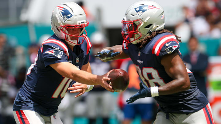 New England Patriots quarterback Drake Maye (10) hands off to running back Rhamondre Stevenson (38) against the Miami Dolphins in the first quarter at Hard Rock Stadium.