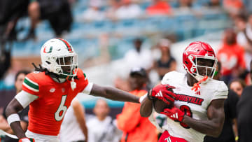Nov 18, 2023; Miami Gardens, Florida, USA; Louisville Cardinals wide receiver Chris Bell (0) catches the football against Miami Hurricanes defensive back Damari Brown (6) during the second quarter at Hard Rock Stadium. Mandatory Credit: Sam Navarro-USA TODAY Sports