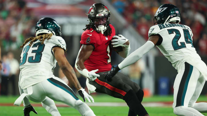 Jan 15, 2024; Tampa, Florida, USA; Tampa Bay Buccaneers running back Rachaad White (1) runs the ball as Philadelphia Eagles cornerbacks Bradley Roby (33) and James Bradberry (24) defend during the first half of a 2024 NFC wild card game at Raymond James Stadium. Mandatory Credit: Kim Klement Neitzel-USA TODAY Sports