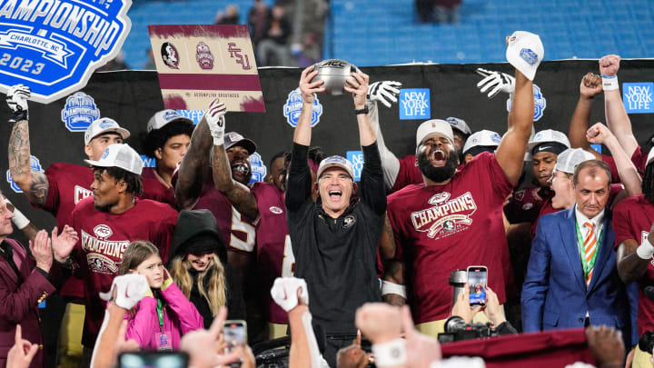 Dec 2, 2023; Charlotte, NC, USA; Florida State Seminoles head coach Mike Norvell raises the ACC Championship trophy with his players after the game against the Louisville Cardinals at Bank of America Stadium. Mandatory Credit: Jim Dedmon-USA TODAY Sports