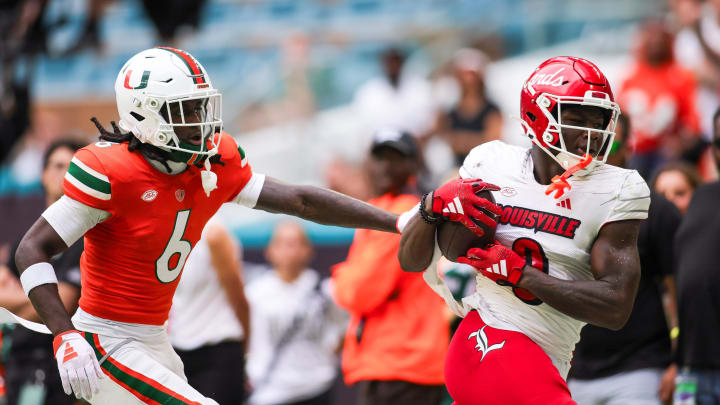 Nov 18, 2023; Miami Gardens, Florida, USA; Louisville Cardinals wide receiver Chris Bell (0) catches the football against Miami Hurricanes defensive back Damari Brown (6) during the second quarter at Hard Rock Stadium. Mandatory Credit: Sam Navarro-USA TODAY Sports